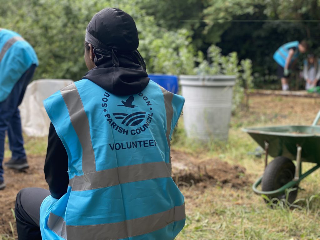 A volunteer sits in a community garden
